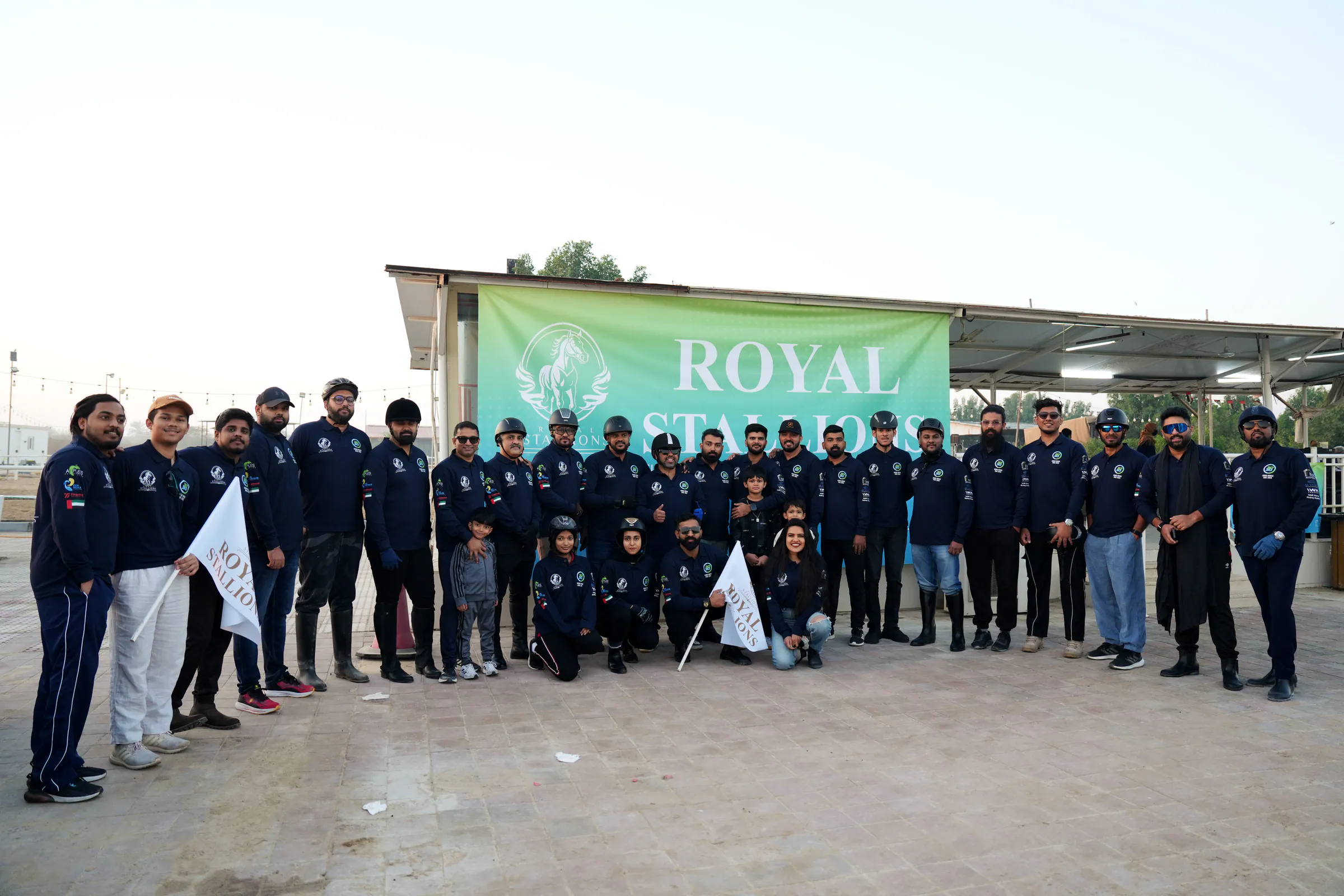 Club members in navy uniforms gathered under a Royal Stallions banner before the National Day ride